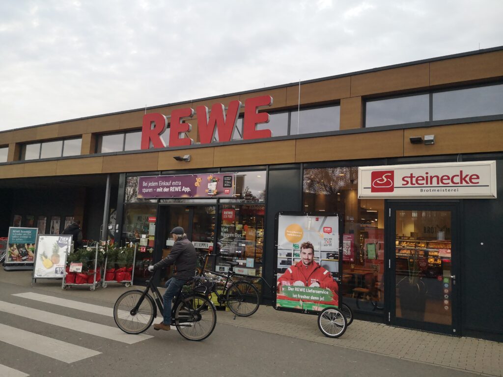 Fahrradwerbung für REWE als Arbeitgeber direkt vor einer Filiale